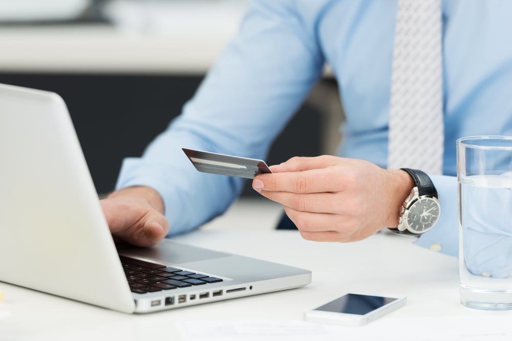 Businessman doing online banking, making a payment or purchasing goods on the internet entering his credit card details on a laptop, close up view of his hands